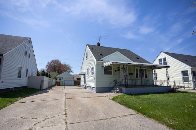 bungalow-style house with a porch, a front yard, a garage, an outbuilding, and fence