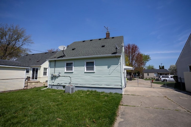 back of property featuring a chimney, a yard, a gate, fence, and central AC