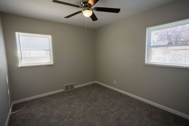 unfurnished room with dark carpet, visible vents, ceiling fan, and baseboards