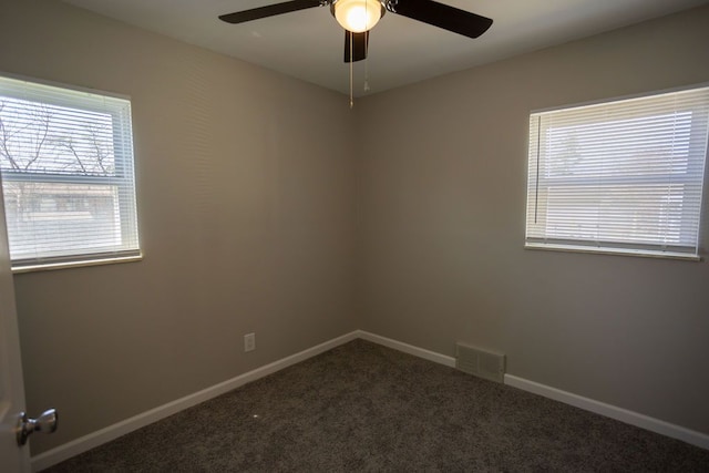 spare room featuring baseboards, visible vents, dark colored carpet, and a ceiling fan