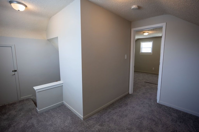 corridor featuring an upstairs landing, a textured ceiling, vaulted ceiling, and carpet floors