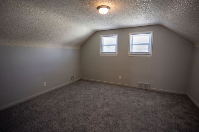bonus room with visible vents, a textured ceiling, and lofted ceiling