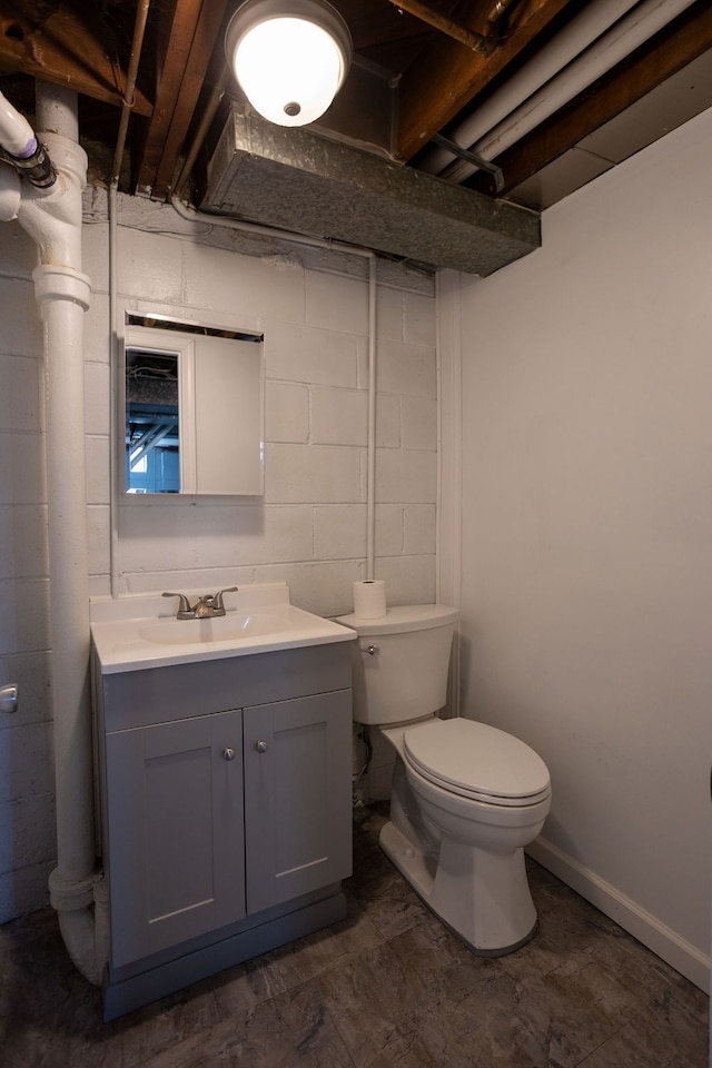 half bath with concrete block wall, toilet, and vanity