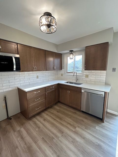 kitchen with light countertops, stainless steel appliances, decorative backsplash, and a sink