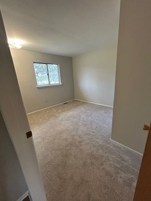 carpeted spare room featuring baseboards