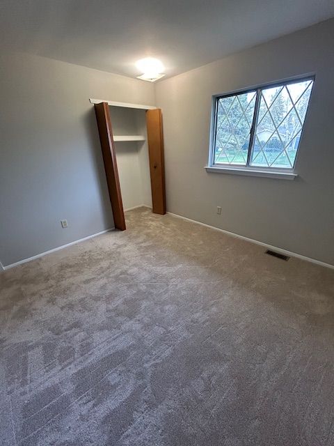 unfurnished bedroom featuring carpet flooring, baseboards, and visible vents