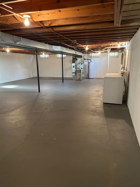 unfinished basement with washer / dryer, heating unit, and gas water heater