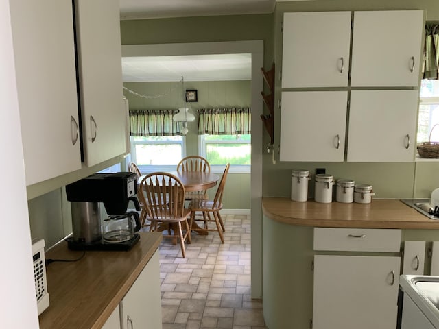 kitchen featuring white cabinetry and brick floor