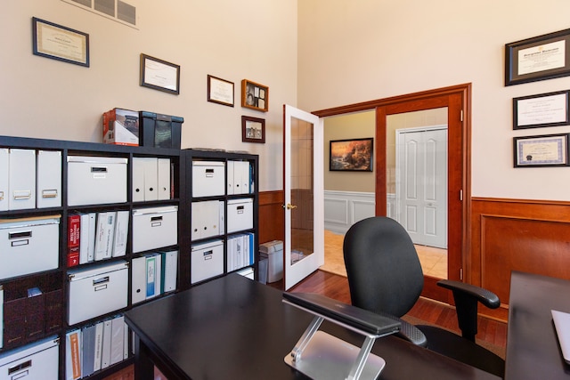 office with wood finished floors, visible vents, french doors, a decorative wall, and wainscoting
