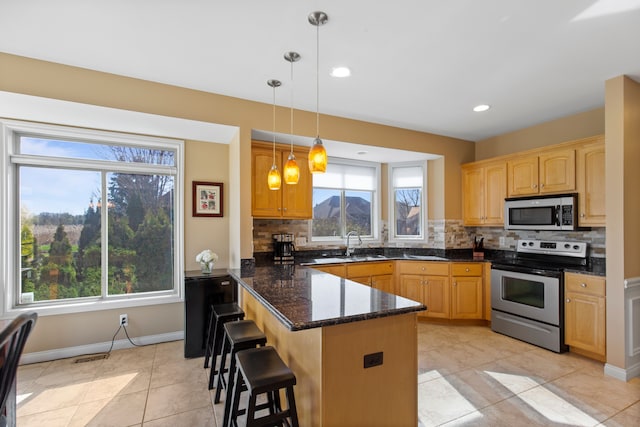 kitchen featuring tasteful backsplash, a sink, a breakfast bar area, a peninsula, and appliances with stainless steel finishes