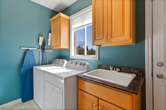 washroom featuring baseboards, a sink, washer and clothes dryer, and cabinet space