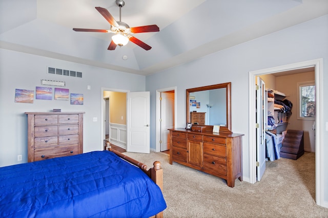 carpeted bedroom with visible vents, a spacious closet, a ceiling fan, a closet, and a raised ceiling