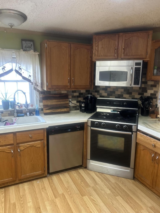 kitchen featuring backsplash, stainless steel appliances, light countertops, and a sink