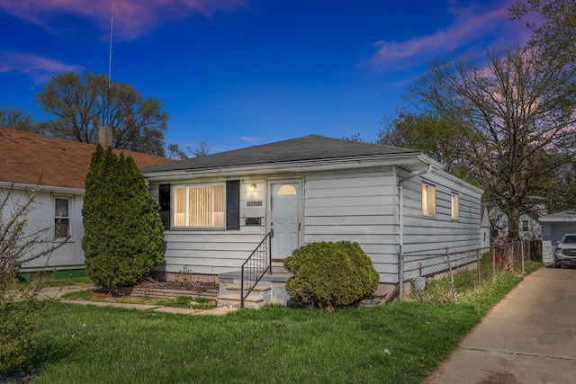 view of front facade with a lawn, fence, and entry steps