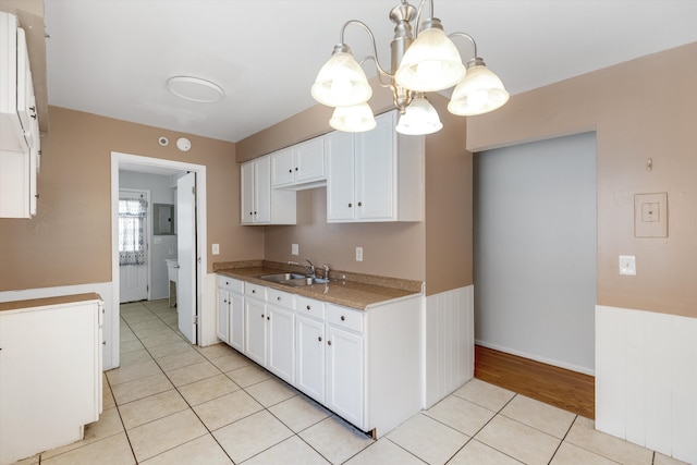kitchen featuring hanging light fixtures, a sink, light tile patterned floors, a notable chandelier, and white cabinetry