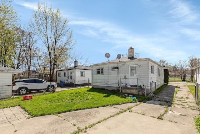 view of front of home featuring fence, a chimney, and a front lawn