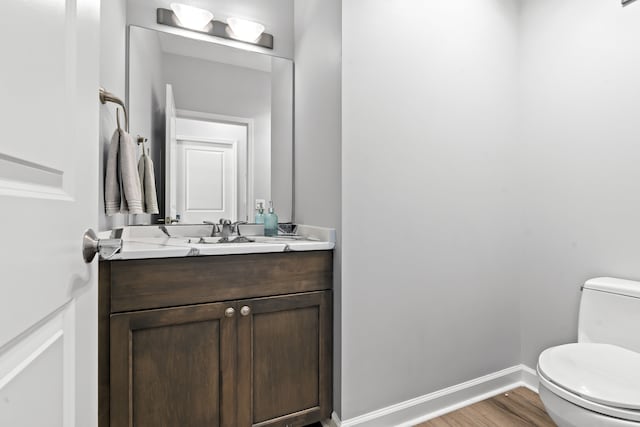 bathroom with wood finished floors, vanity, toilet, and baseboards