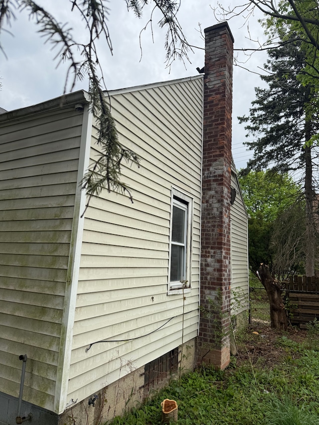 view of side of property with crawl space, fence, and a chimney