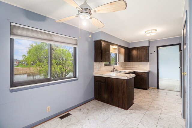 92 Brookfield Dr, Oxford, MI 48371 - kitchen with dark brown cabinetry, light countertops, a peninsula, light marble finish floors, and crown molding