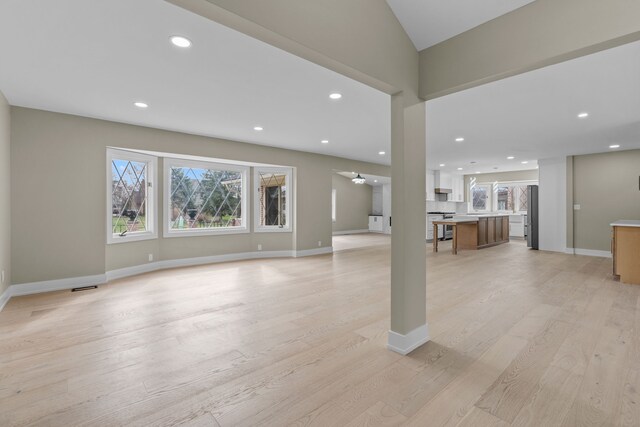 unfurnished living room with recessed lighting, a healthy amount of sunlight, and light wood finished floors