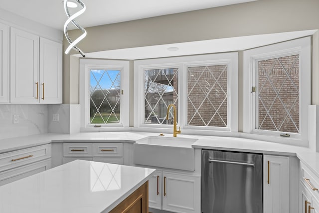 kitchen featuring backsplash, dishwasher, white cabinetry, and a sink