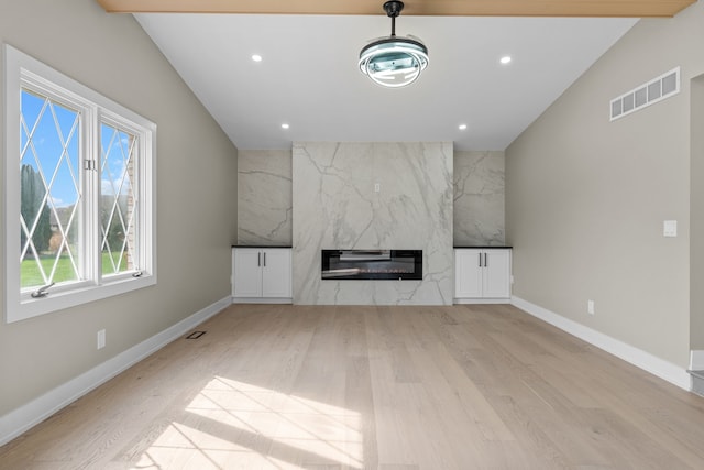 unfurnished living room with wood finished floors, visible vents, recessed lighting, and a high end fireplace