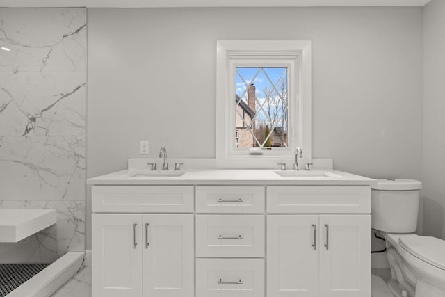 bathroom with marble finish floor, a sink, a marble finish shower, and toilet