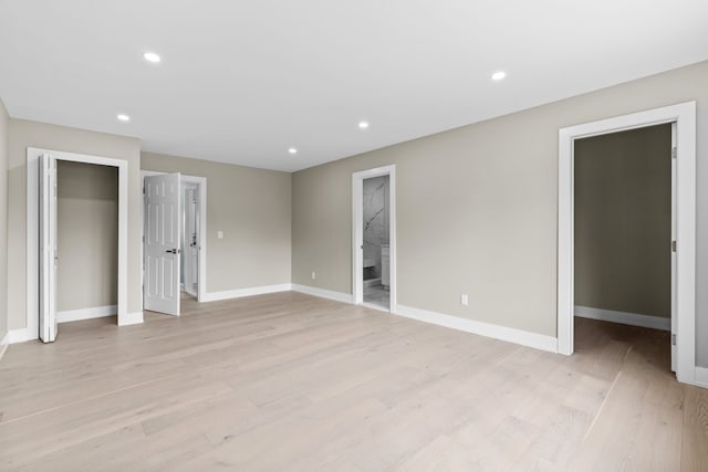 unfurnished bedroom featuring light wood-type flooring, baseboards, recessed lighting, and a walk in closet