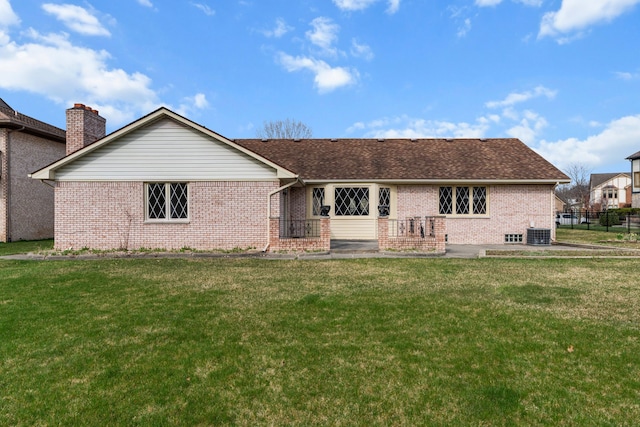 back of house with a lawn, brick siding, and roof with shingles