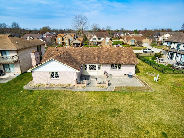 back of property with a residential view, fence, brick siding, a yard, and a patio