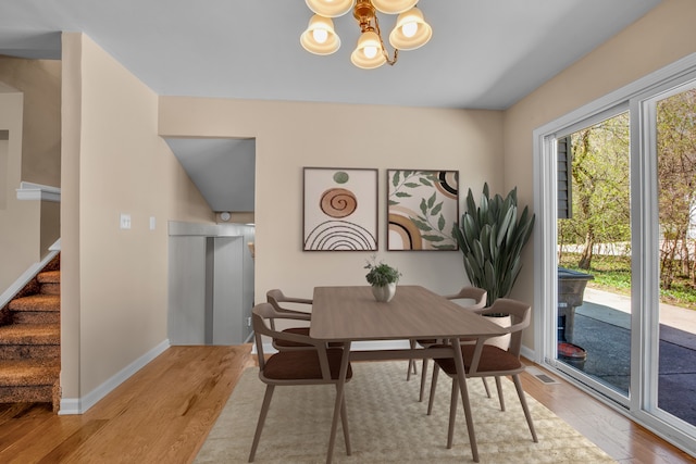 19737 Clement Rd, Northville, MI 48167 - dining space with a chandelier, wood finished floors, stairs, and baseboards