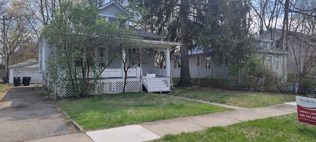 traditional style home featuring covered porch, a front yard, and a garage