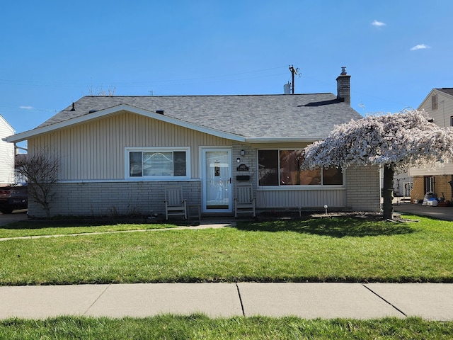 view of front of home featuring brick siding, roof with shingles, a chimney, and a front lawn