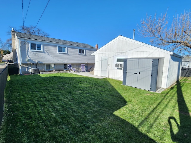 back of house with an outbuilding, central air condition unit, fence, a lawn, and a shed
