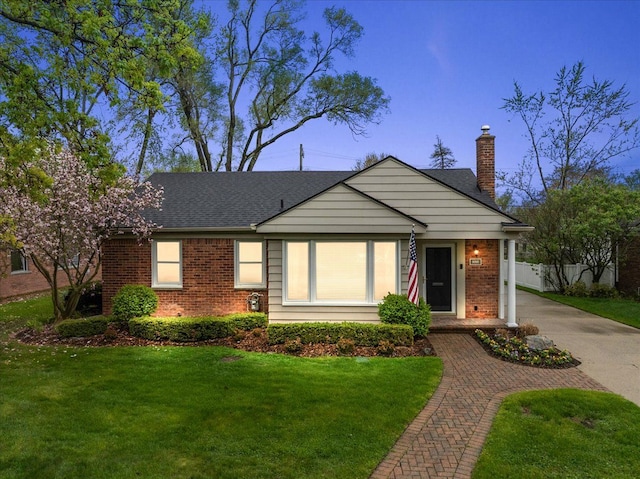 view of front of home featuring a chimney, a front lawn, and brick siding