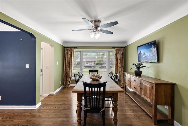 dining area with baseboards, arched walkways, ceiling fan, and dark wood-type flooring