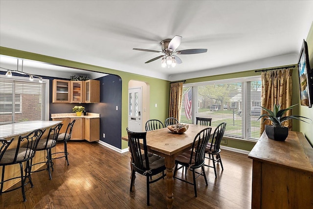 dining room featuring baseboards, arched walkways, and dark wood finished floors