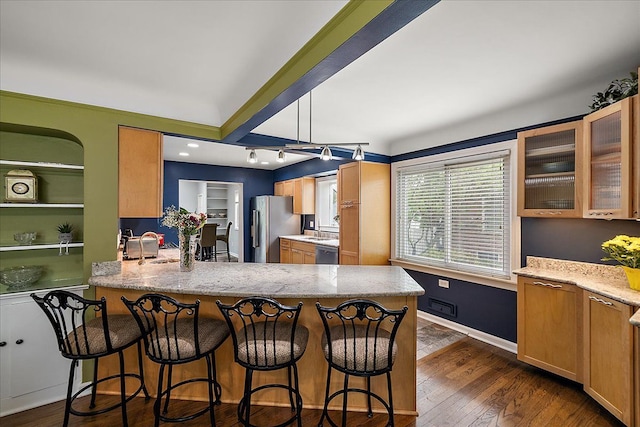 kitchen featuring light stone counters, a peninsula, appliances with stainless steel finishes, and glass insert cabinets