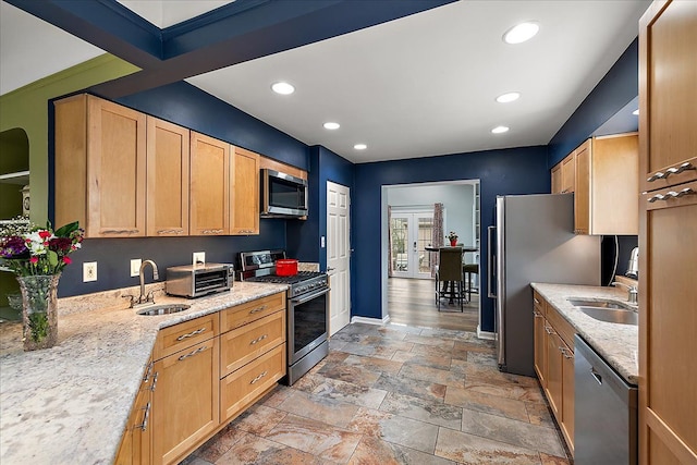 kitchen with appliances with stainless steel finishes, a sink, recessed lighting, baseboards, and stone tile flooring