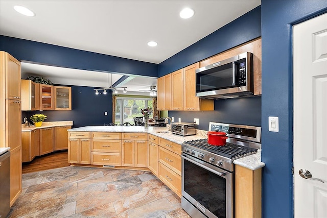 kitchen with light brown cabinetry, a peninsula, appliances with stainless steel finishes, and light countertops
