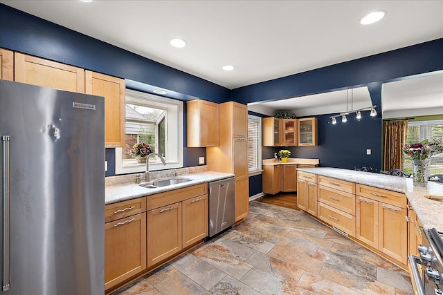 kitchen featuring a sink, light brown cabinets, stone tile floors, stainless steel appliances, and glass insert cabinets