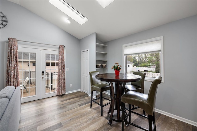 dining area with baseboards, french doors, lofted ceiling with skylight, and wood finished floors