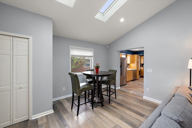 dining room featuring light wood-style floors, recessed lighting, baseboards, and a skylight