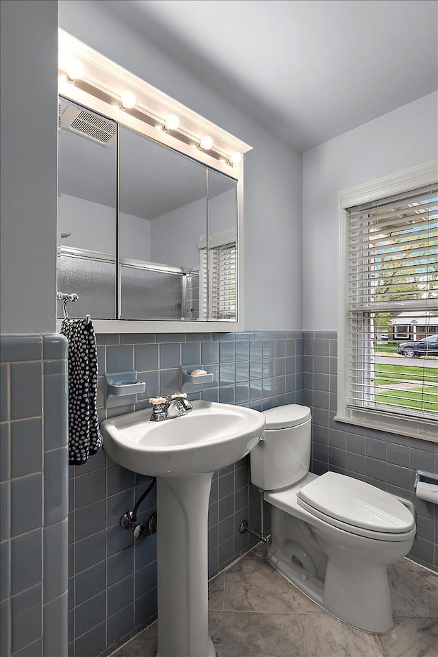 bathroom featuring toilet, tile walls, visible vents, and a wainscoted wall