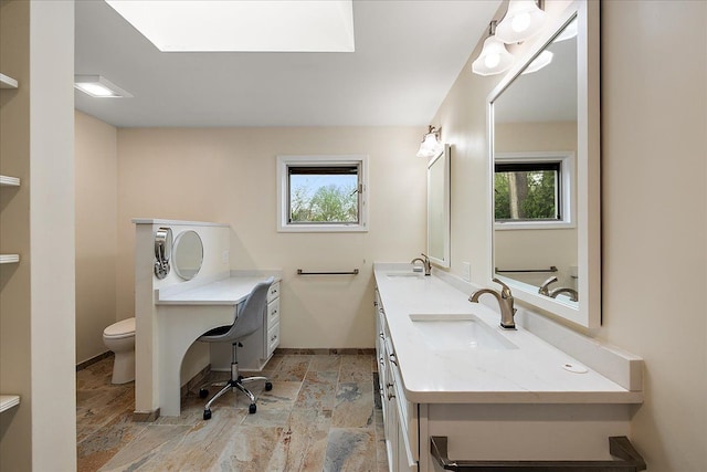 bathroom featuring a sink, baseboards, toilet, and a healthy amount of sunlight