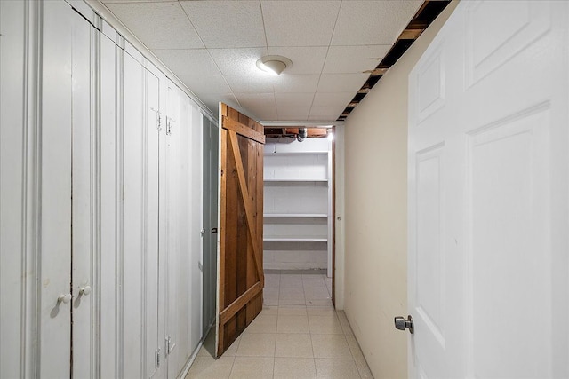 corridor featuring a paneled ceiling and light tile patterned floors