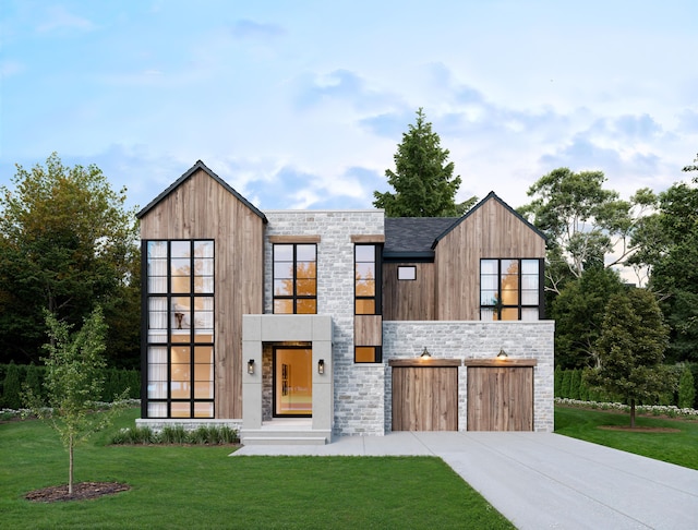modern home with driveway, an attached garage, a front lawn, and stone siding