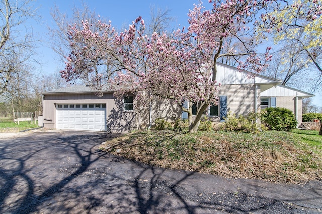 obstructed view of property featuring brick siding, aphalt driveway, and a garage