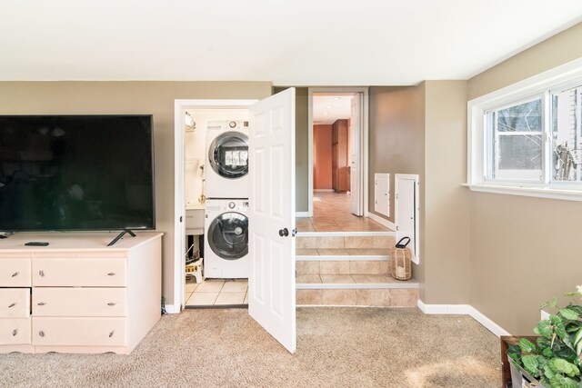 washroom with light carpet, stacked washing maching and dryer, laundry area, and light tile patterned floors