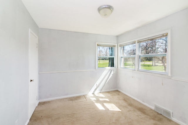 unfurnished room with carpet, visible vents, and baseboards